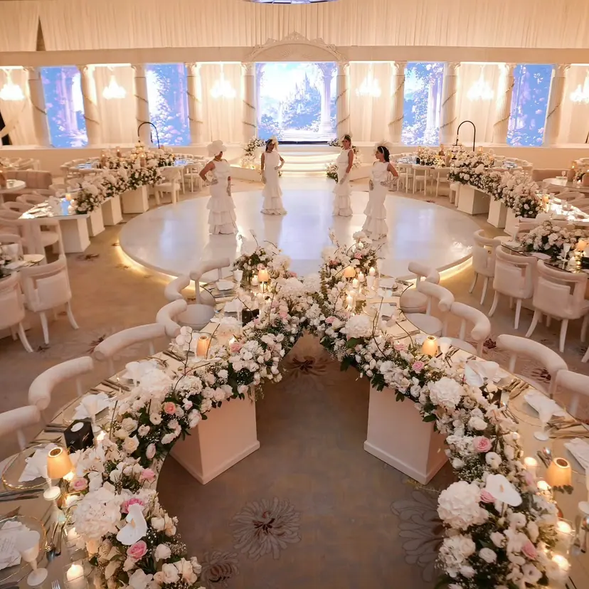 A curving aisle of white and blush roses, with lamp-lit tables on both sides, leading to the round dance floor of the Fairmont Amman ballroom