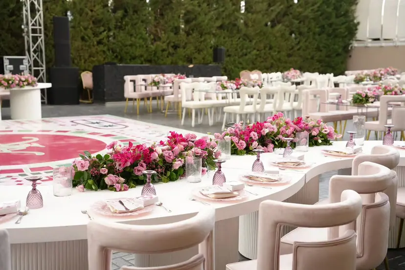 A long white table with pink flower runners and cream chairs beside the painted dance floor