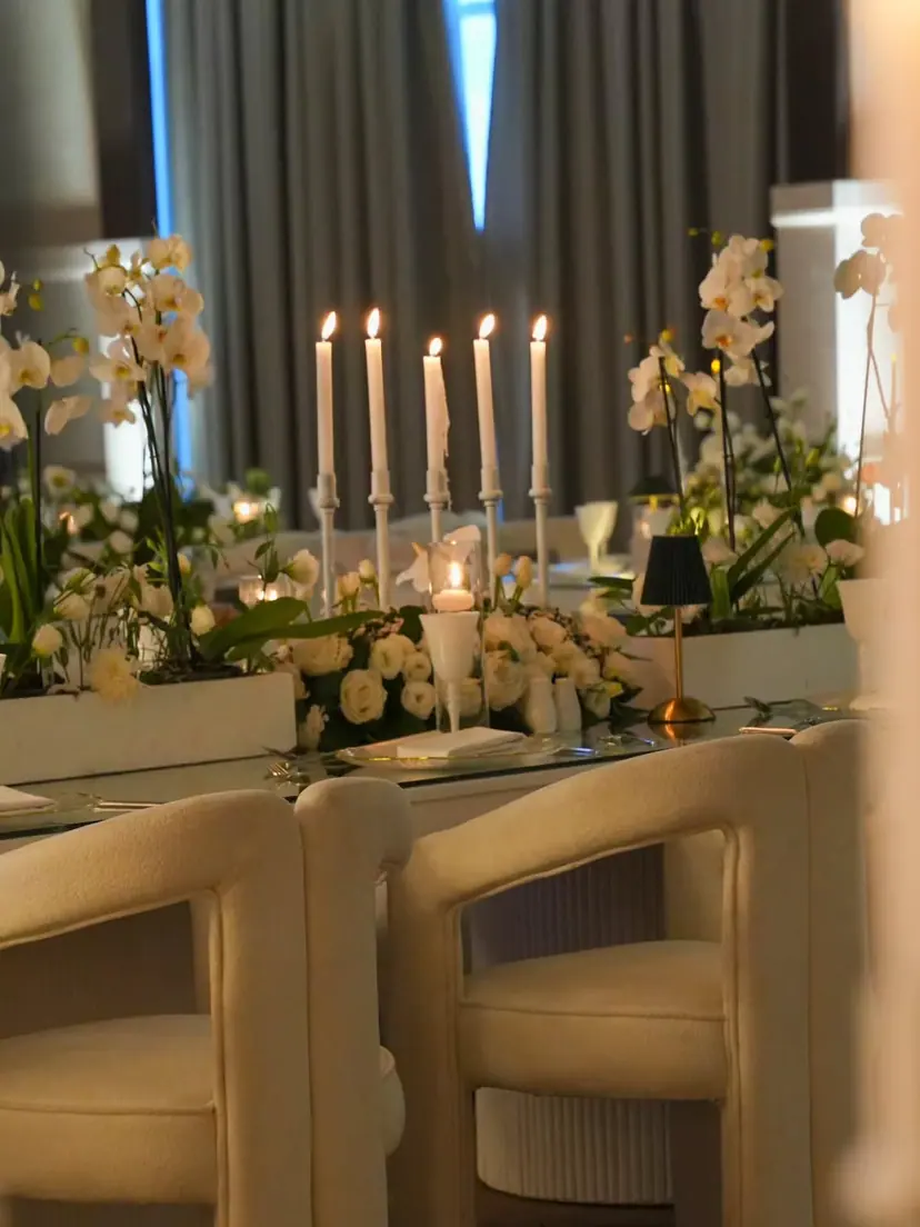 Cream bouclé chairs, white orchids and tall candles along a wedding table